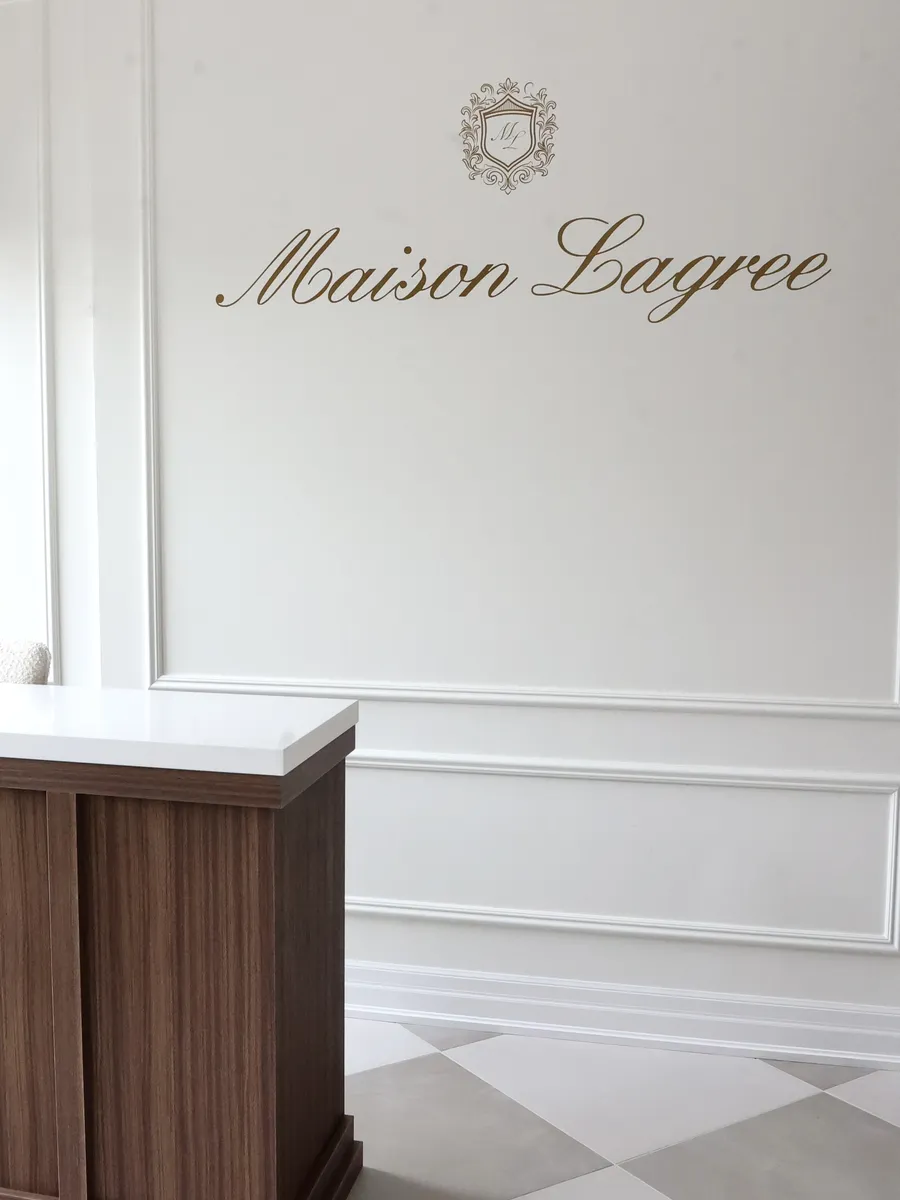 The welcome desk with the gold Maison Lagree script and crest on the wall