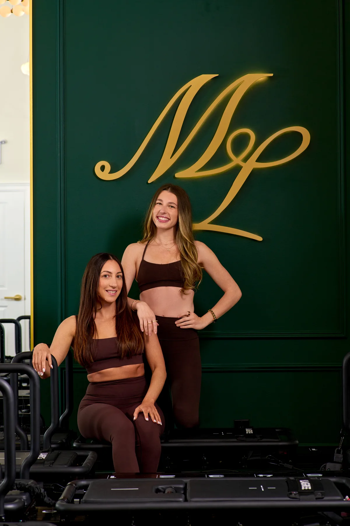 Members hold a lunge beneath the gold monogram, deep in the working phase
